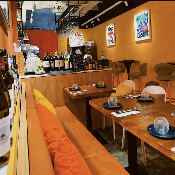 The owner's phone photo of the restaurant interior: orange walls, wine shelves, a mosaic-tile mirror sign